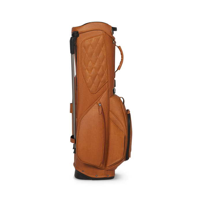 A tan leather Titleist LINKSLEGEND Classic Members II Golf Stand Bag shown from the side on a clean white background, featuring a quilted diamond pattern on the upper section, multiple zippered pockets, and a telescoping silver stand.