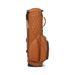 A tan leather Titleist LINKSLEGEND Classic Members II Golf Stand Bag shown from the side on a clean white background, featuring a quilted diamond pattern on the upper section, multiple zippered pockets, and a telescoping silver stand.