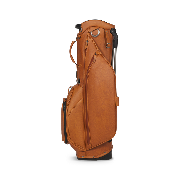 A side profile view of a tan leather Titleist LINKSLEGEND Classic Members II Golf Stand Bag with a telescoping handle and multiple zippered pockets, set against a plain white background.