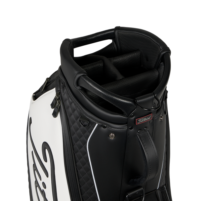 Close-up of a black and white Titleist Tour Series Tour Golf Bag II showing the top handle, padded interior, zipper, and a small red Titleist logo badge.