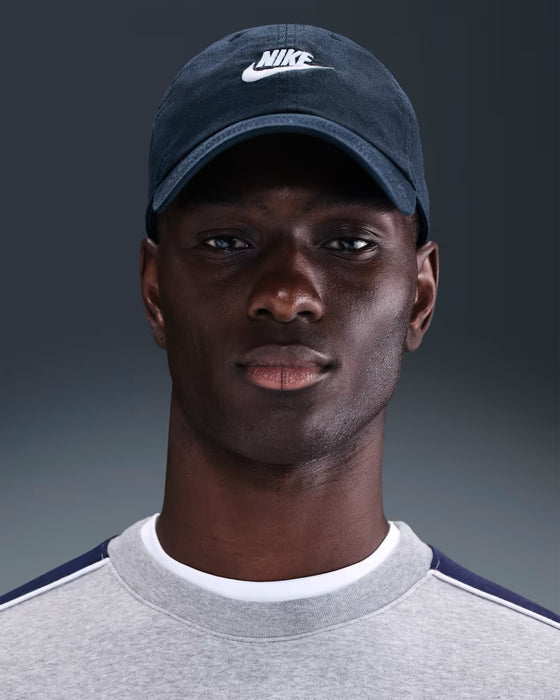 Nike Club Futura Unstructured Golf Cap in obsidian blue with a white logo, worn by a model in a front-facing view.