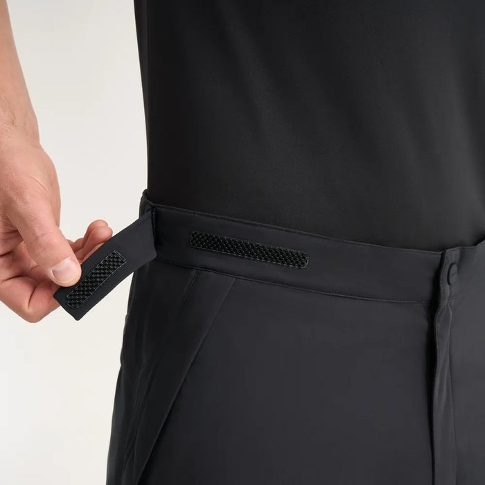 PING AquaDrive Pro men's black waterproof golf trousers, showing a close-up of the adjustable velcro waist tab.