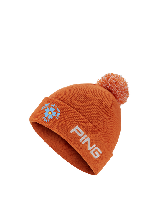 PING Cresting Knit Fore Get Me Not golf beanie in russet with a pom-pom, featuring embroidered logo and flower detail.