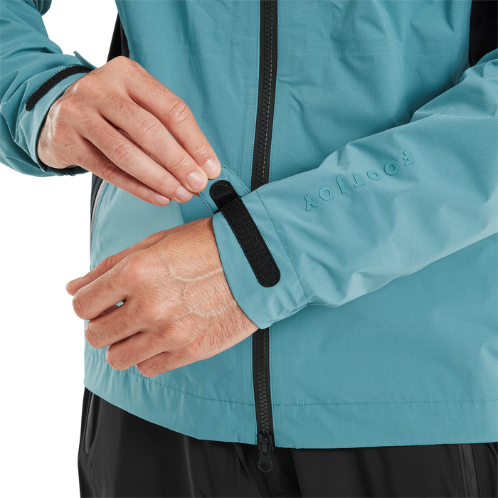 FootJoy ARCUS waterproof golf jacket in teal, showing a close-up of the adjustable Velcro cuff and branded sleeve detail.