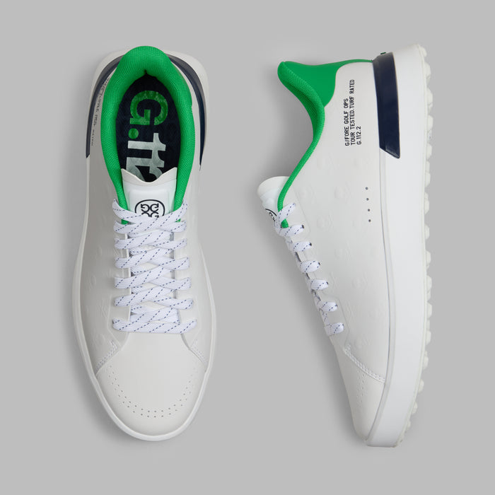 G/FORE G.112 Embossed Skull & Tees Spikeless Golf Shoes in white with green and navy accents, view from above with one shoe laying on its side