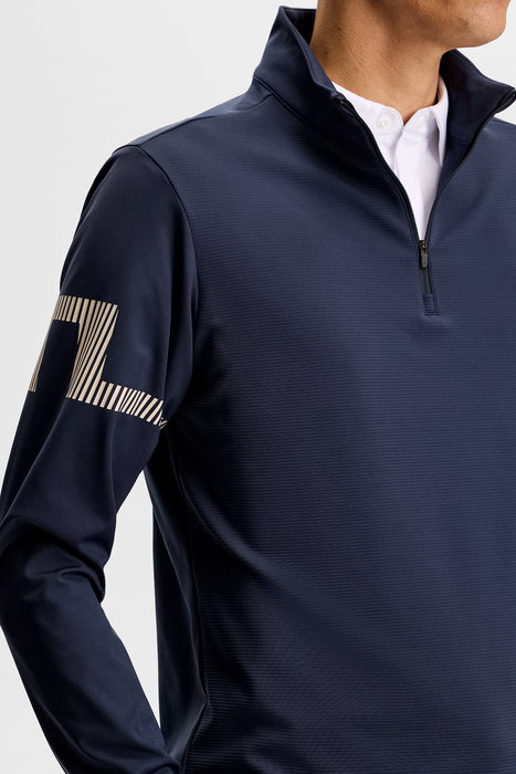 J.Lindeberg Heath Strike Quarter Zip Golf Mid Layer in jl navy on model, close up on jl logo on arm
