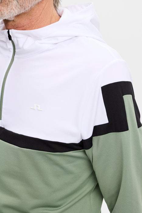 white, green and black J.Lindeberg Sole Golf Hoodie on model, close up of JL logo