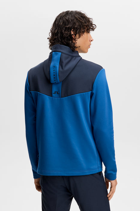 Back view of J.Lindeberg Maclean quarter zip golf hoodie in blue and navy with branded hood detailing.