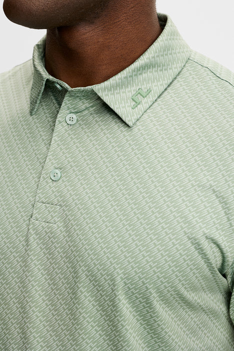 J.Lindeberg Tod Print Golf Polo Shirt in hedge green on a model, lose up of JL logo on collar