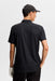 J.Lindeberg Kofe Golf Polo Shirt in black, showing full front of the polo in black on a model wearing a hat showing back of shirt