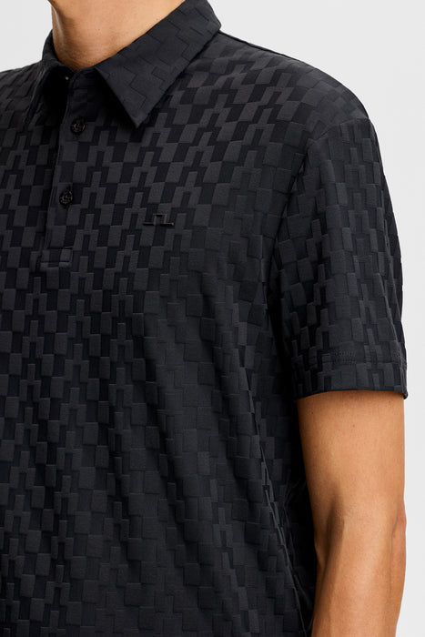 J.Lindeberg Kofe Golf Polo Shirt in black, showing full front of the polo in black on model, showing a close up of the raised pattern and tonal JL logo