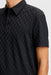 J.Lindeberg Kofe Golf Polo Shirt in black, showing full front of the polo in black on model, showing a close up of the raised pattern and tonal JL logo