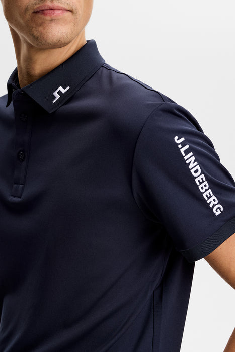 J.Lindeberg Tour Tech Golf Polo Shirt in navy on model, close up of both logos including one on arm