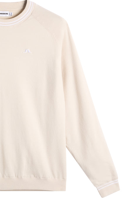 close up of JL logo on the J.Lindeberg Kenny Windbreaker Knit Golf Sweatshirt in cream