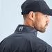 Man wearing a black jacket with a logo on the collar against a light blue background