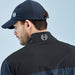 Rear view of a man wearing a black PING AquaDrive waterproof golf jacket and matching navy cap with logo detail.