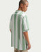 Male model wearing Nike Dri-FIT Fairway Fresh Loose Golf Polo Shirt in green and white facing away