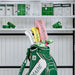 Green golf bag with 'TaylorMade' branding in a storage shed with gardening tools and supplies.