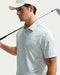 golf holding a club wearing Nike Dri-FIT Micro-Print Golf Polo Shirt in white and green