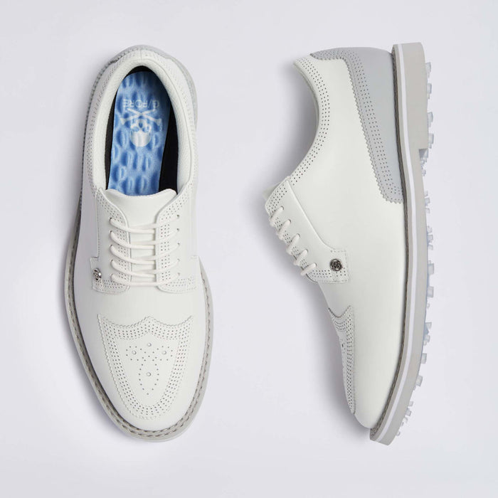 A pair of white G/FORE Gallivanter Leather Brogue Men's Spikeless Golf Shoes shown from the top and side views on a light grey background. The shoes feature perforated detailing on the toe, white laces, and a light grey sole with a textured tread.