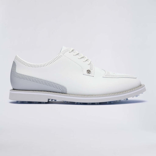 A white leather G/FORE Gallivanter Leather Brogue Men's Spikeless Golf Shoes with perforated details, a small silver-tone logo badge on the side, and a white sole with visible golf club tips, shown against a light grey studio background.