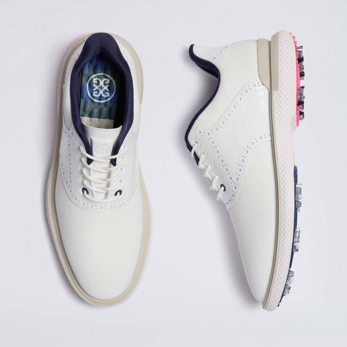 A pair of white G/FORE Gallivan2R Brogue Saddle Men's Golf Shoes shown from the top and side views on a light grey background. The shoes feature navy blue lining, white laces, and pink and silver golf club spikes on the sole.