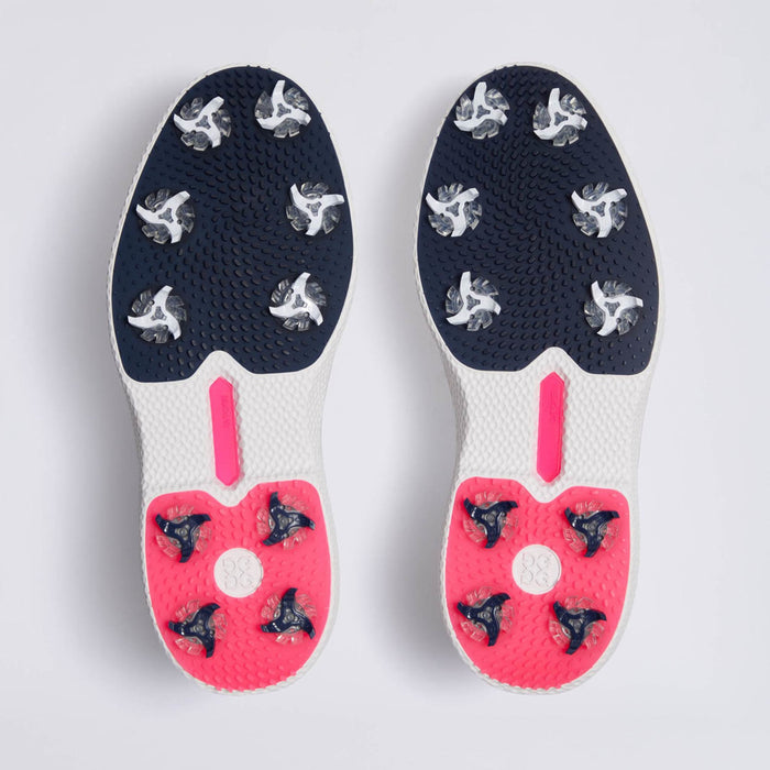 A pair of G/FORE Gallivan2R Brogue Saddle Men's Golf Shoes soles viewed from above, featuring a dark navy blue textured upper section with white and clear spikes, and a bright pink lower section with black and clear spikes, separated by a white midsole with a pink accent.