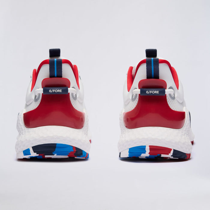 A pair of white, red, and blue G/FORE MG4+ O2 Perforated Men's Spikeless Golf Shoes shown from the back on a light grey studio background. The shoes feature a white textured midsole, a glossy red heel counter, and red and blue accents on the collar, tongue, and outsole.