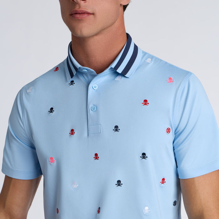 close up on model of the G/FORE Embroidered Tech Jersey Men's Golf Polo Shirt in light blue with multi colour all over logos