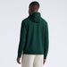 A man viewed from the back wearing a dark green G/FORE Pebble Quilted Men's Golf Hoodie and light beige pants, set against a plain light grey studio background.