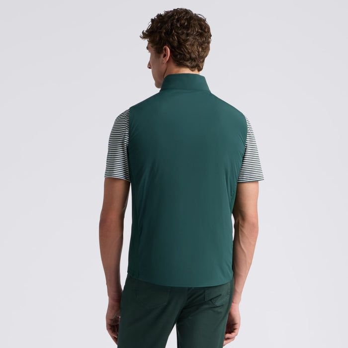 A man viewed from the back wearing a dark green G/FORE The Maverick Hybrid Stretch 2.0 Men's Golf Gilet with black and white striped sleeves, paired with dark green pants, against a light grey studio background.