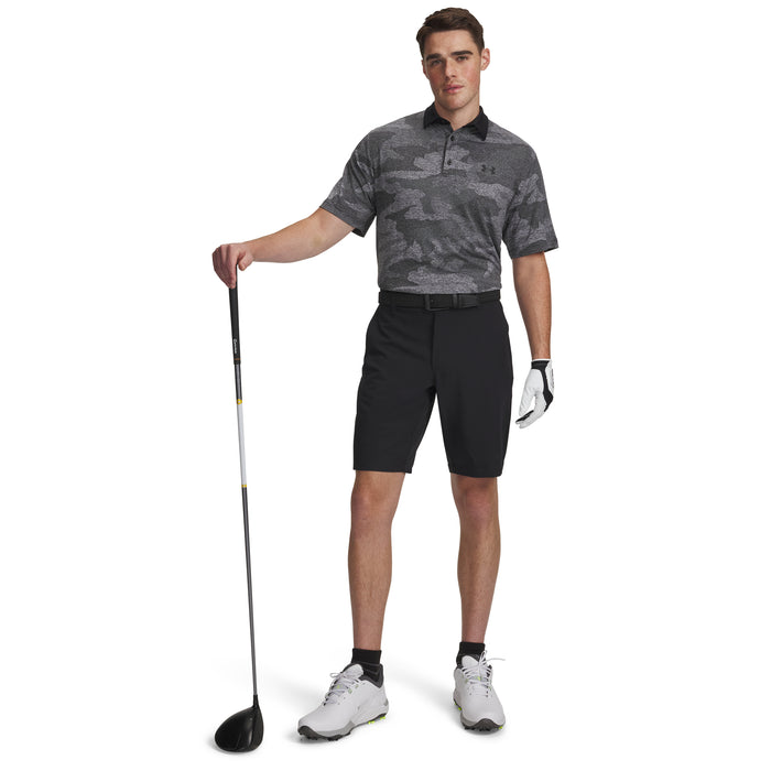 A model wearing Under Armour Drive Golf Shorts in black, full view of the golfers Under Armour outfit. Model is holding a golf club