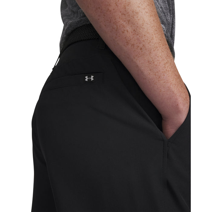 A model wearing Under Armour Drive Golf Shorts in black, close up of the front right pocket and small UA logo