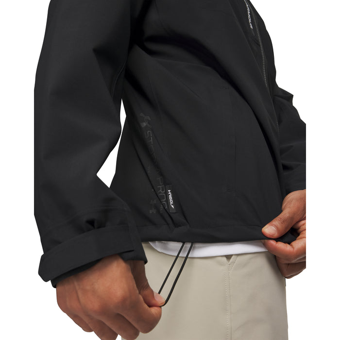 Side view of a black Under Armour Drive Pro waterproof golf jacket showing the adjustable hem drawstring detail.
