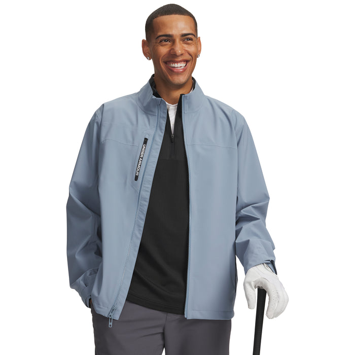 Under Armour Drive Pro waterproof golf jacket in blue wind with a front zip and high collar, worn by a smiling golfer.